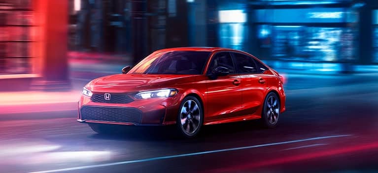 2027 Honda Civic Sedan Sport Touring Hybrid in Rallye Red front three-quarter view driving through a city (Compact Sedan)